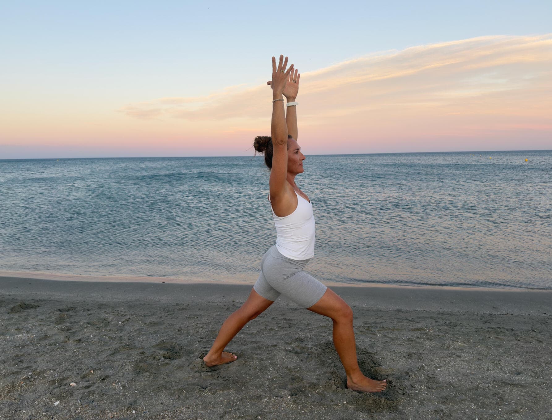 Nina in der Krieger-Pose mit gestreckten Armen am Meer